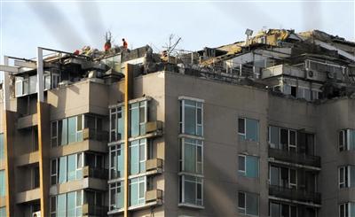 　　昨日，身穿橘黃色馬甲的工作人員在人濟(jì)山莊樓頂拆除違章建筑。新京報(bào)記者 吳江 攝