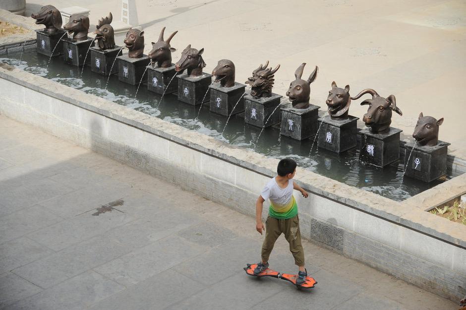 圖為一名市民從獸首旁經(jīng)過。