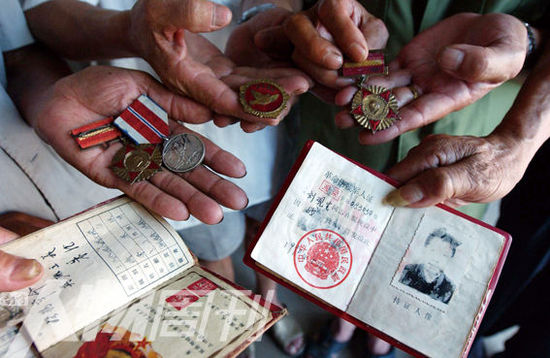幾位志愿軍老兵展示自己的立功證、傷殘軍人證與勛章