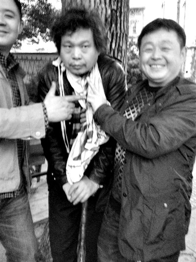 兩名接訪人員與患有癌癥的訪民段新德合影時(shí)，面帶笑容擺出勝利的手勢(shì)。