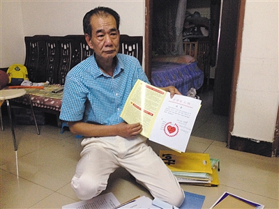 翻出一家網(wǎng)站贈(zèng)予的“中國(guó)好人”證書(shū)，區(qū)少坤單膝跪在地上，“你看，我是中國(guó)好人啊。” 范春旭 攝