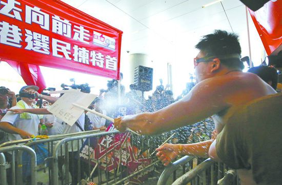 17日，在香港立法會(huì)外，一名反對(duì)政改的男子向支持派人群投擲標(biāo)牌。