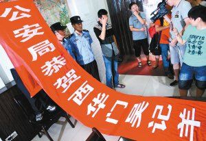 面對警方收繳的條幅，老板楊某也不好意思地用手遮擋臉