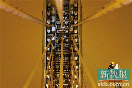 截至今日零時(shí)，男子仍未有下橋舉動(dòng)。圖為公安和消防人員乘消防云梯在高空上和男子交談。