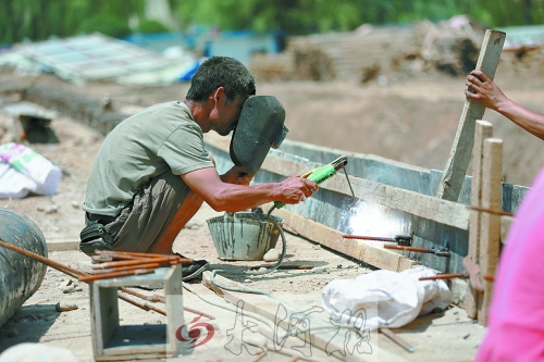 　正午陽(yáng)光下，工地上的焊接工人還在認(rèn)真工作。