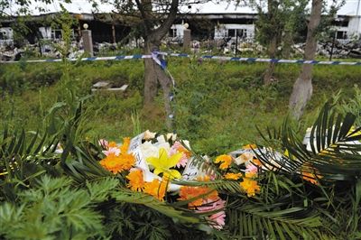 昨日，吉林省德惠市吉林寶源豐禽業(yè)有限公司燃燒事故現(xiàn)場警戒線外，遇難者家屬在路邊擺放了花圈祭奠逝去的親人。吳江 攝