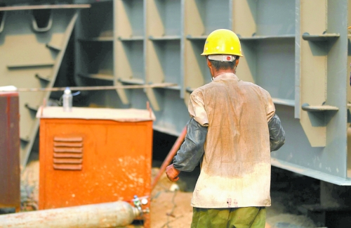 工地上，一建筑工人的衣服被汗水浸透。