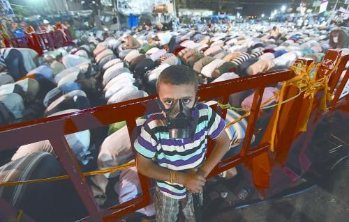 當(dāng)?shù)貢r(shí)間28日晚，在埃及開羅納賽爾城，一名小男孩頭戴防毒面具參加穆兄會(huì)的集會(huì)示威。