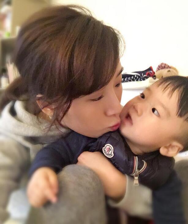 照片中李念狂吻兒子，小寶貝自顧自地玩著。