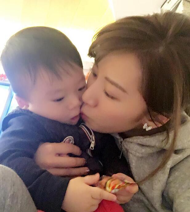 照片中李念狂吻兒子，小寶貝自顧自地玩著。