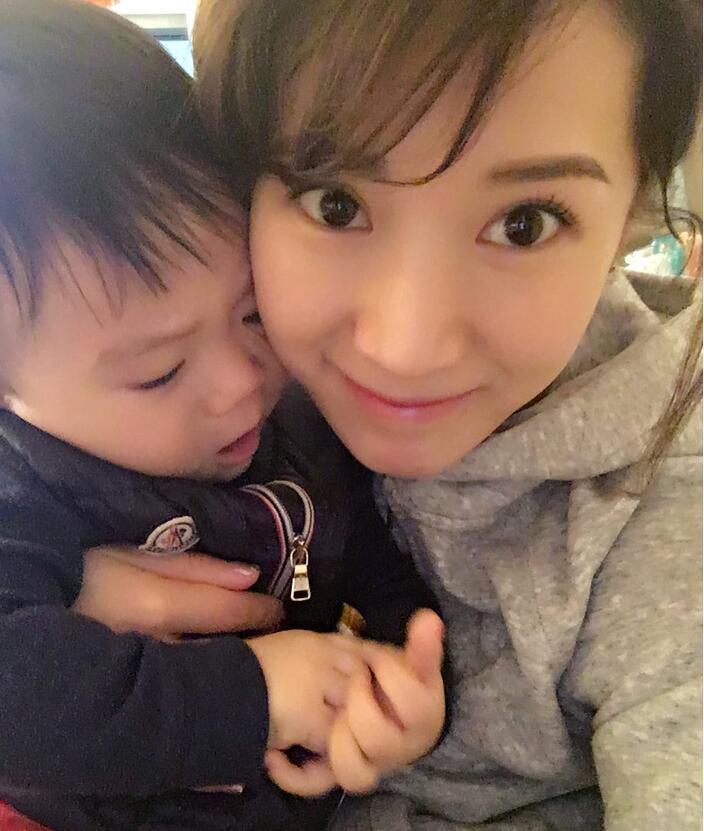 照片中李念狂吻兒子，小寶貝自顧自地玩著。