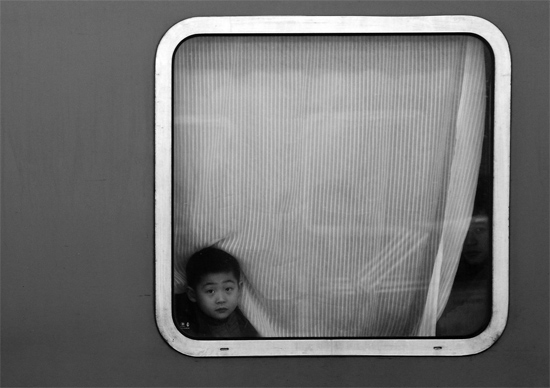 一個孩子把頭伸向窗外，他想再看送別的親人一眼