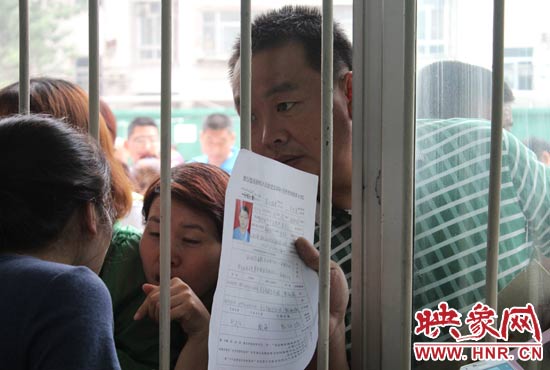 不少家長(zhǎng)擠在報(bào)名窗口前咨詢報(bào)名事宜。