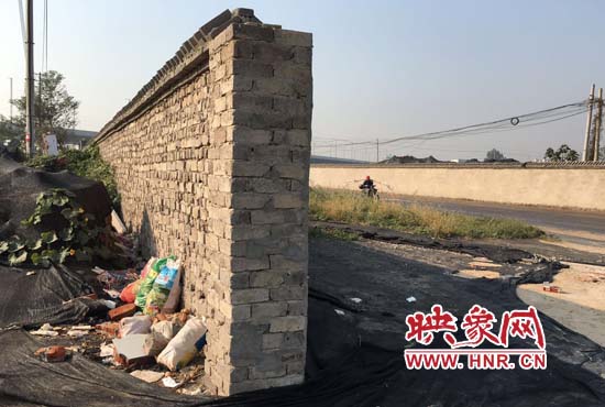 一墻之隔，一邊是道路，一邊是垃圾和荒草，市民質(zhì)疑其為遮羞墻。