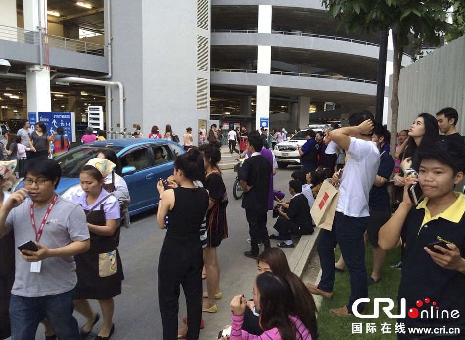 當(dāng)?shù)貢r(shí)間2014年5月5日，泰國(guó)清萊，工人們站在一棟大樓外避難。