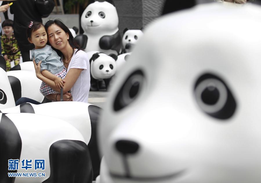 6月2日，一位家長帶著孩子在上海街頭和大熊貓模型合影。