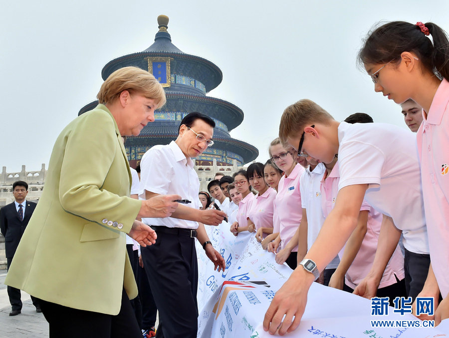 李克強(qiáng)同默克爾在紀(jì)念橫幅上簽名。