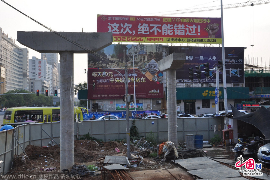 過街天橋一側(cè)的橋樁早已打好,可是對面的郵政銀行網(wǎng)點依舊在照常營業(yè)。