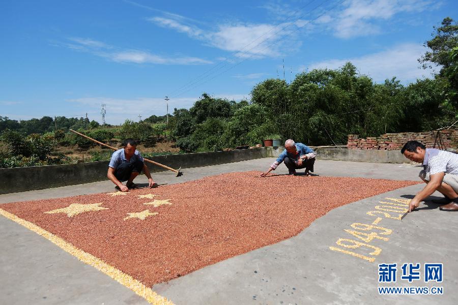 村民馬玉明（左一）用豐收的高粱和玉米在院壩里擺國(guó)旗為祖國(guó)慶生。