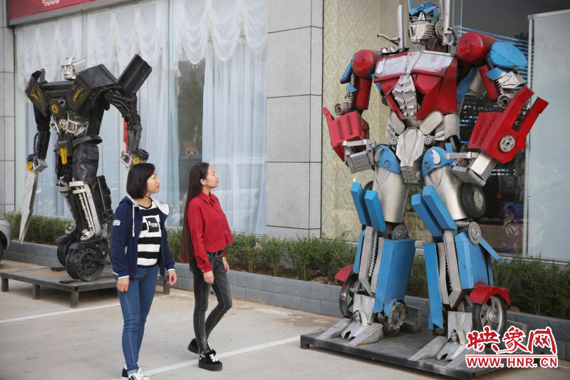 10月14日，市民在參觀河南省平頂山市寶豐縣一家企業(yè)門(mén)前的“變形金剛”。