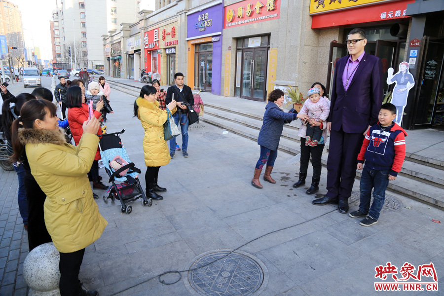 過路市民爭相與“巨人”合影。