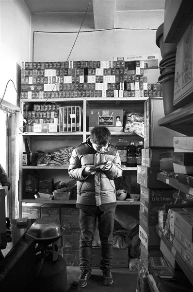 1月21日，周瑋在自家的超市里玩計(jì)算器。