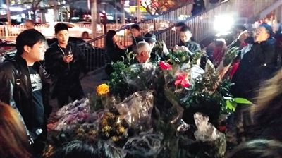 昨晚7時許，三里屯太古里西邊附近一過街天橋旁邊，聞訊而至的網(wǎng)友圍住了賣花老人，爭相買花。 網(wǎng)友“行者橙子”供圖